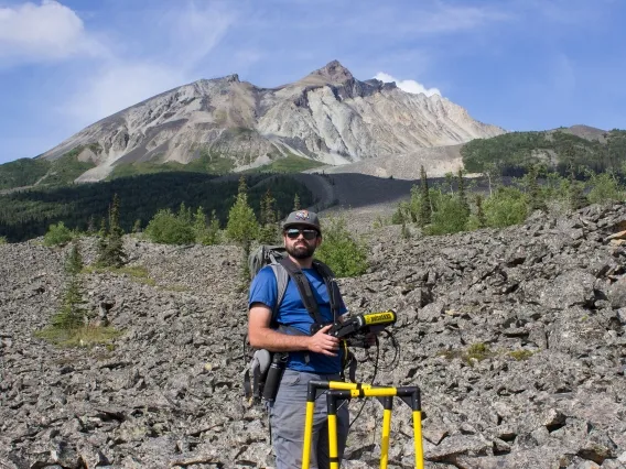 man standing on rocky terrain with electrical equipment