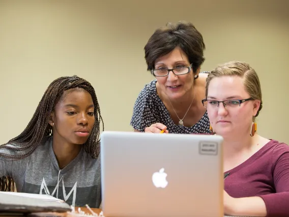 A professor and two students working on a computer