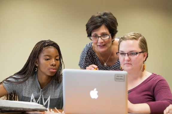 A professor and two students working on a computer